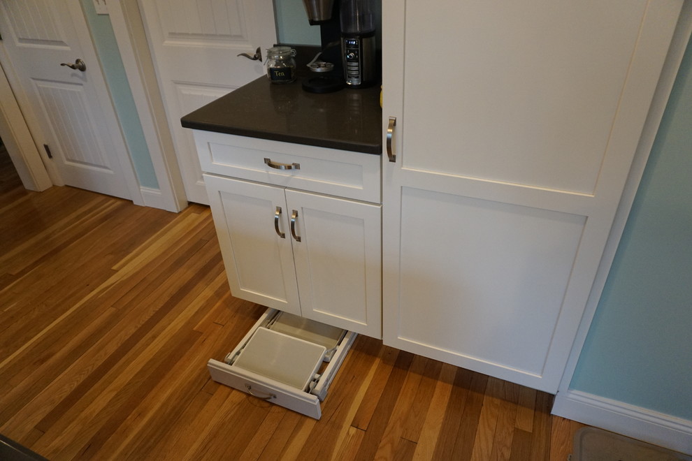 Example of a mid-sized transitional u-shaped medium tone wood floor eat-in kitchen design in Boston with an undermount sink, shaker cabinets, gray cabinets, quartz countertops, black backsplash, stainless steel appliances and an island