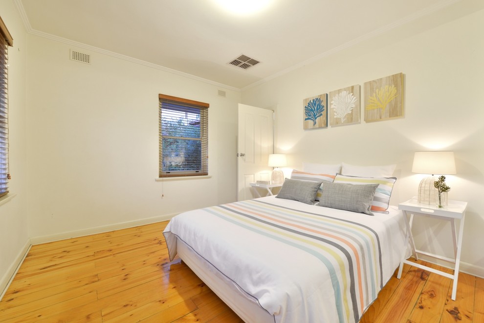 This is an example of a mid-sized beach style master bedroom in Adelaide with light hardwood floors.