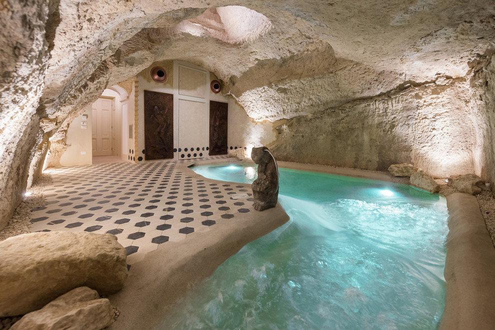 This is an example of a small eclectic indoor custom-shaped pool in Other with natural stone pavers.
