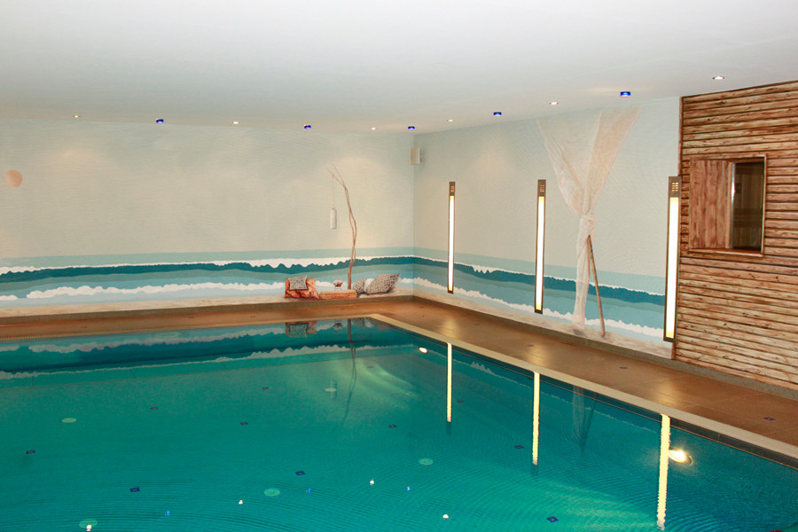 Cette photo montre une grande piscine intérieure bord de mer rectangle avec des pavés en pierre naturelle.