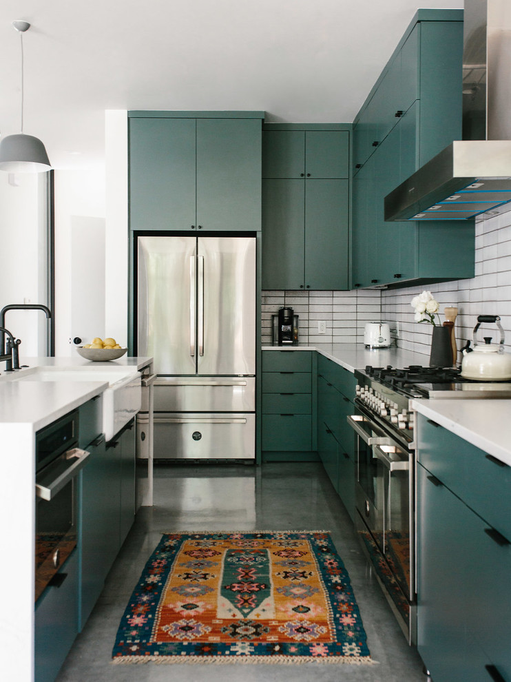 Mid-sized contemporary l-shaped eat-in kitchen in Austin with a farmhouse sink, flat-panel cabinets, green cabinets, quartzite benchtops, white splashback, brick splashback, stainless steel appliances, concrete floors, with island, grey floor and white benchtop.