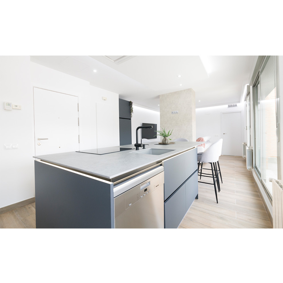 Large scandinavian eat-in kitchen in Madrid with an undermount sink, grey splashback, stainless steel appliances, with island, brown floor and grey benchtop.