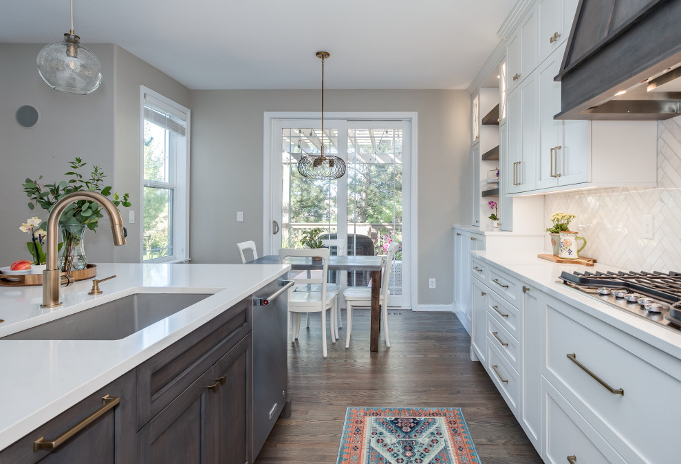 Inspiration for a large transitional galley medium tone wood floor and brown floor open concept kitchen remodel in Denver with an undermount sink, shaker cabinets, white cabinets, quartz countertops, beige backsplash, marble backsplash, stainless steel appliances, an island and white countertops