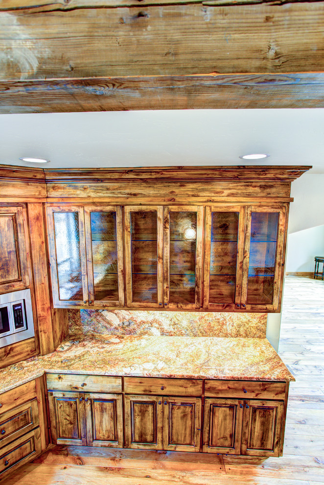 Kitchen pantry - large rustic u-shaped medium tone wood floor kitchen pantry idea with a drop-in sink, glass-front cabinets, medium tone wood cabinets, beige backsplash, stainless steel appliances and an island