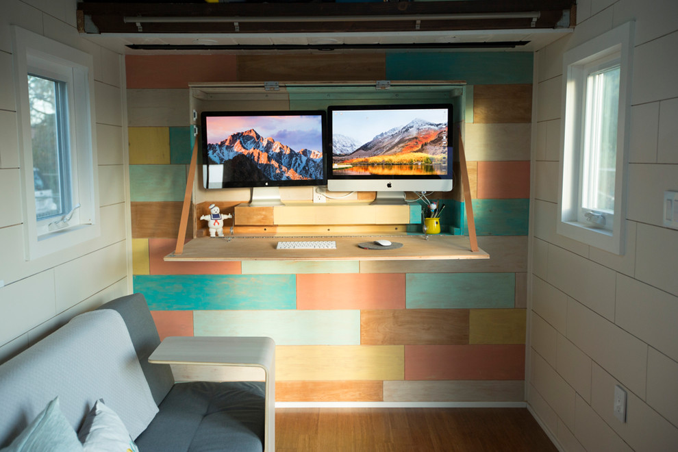 This is an example of a small scandinavian home office with multi-coloured walls, bamboo floors, a built-in desk and brown floor.