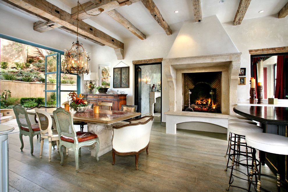 Photo of a mediterranean dining room in Orange County with white walls and a standard fireplace.