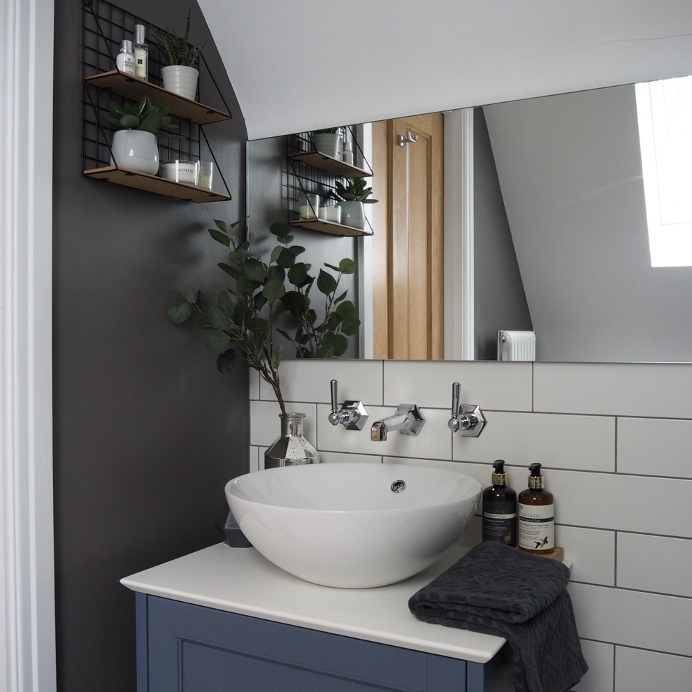 This is an example of a small scandinavian master bathroom in Other with shaker cabinets, blue cabinets, an alcove shower, a wall-mount toilet, white tile, ceramic tile, grey walls, ceramic floors, engineered quartz benchtops, grey floor, a hinged shower door and white benchtops.