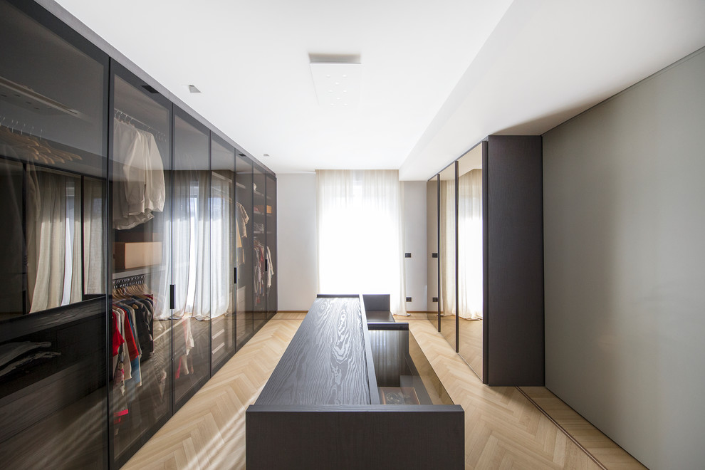Contemporary dressing room in Turin with glass-front cabinets, light hardwood floors and beige floor.
