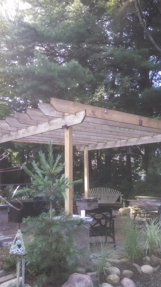 Mid-sized traditional backyard patio in New York with a water feature, natural stone pavers and a pergola.