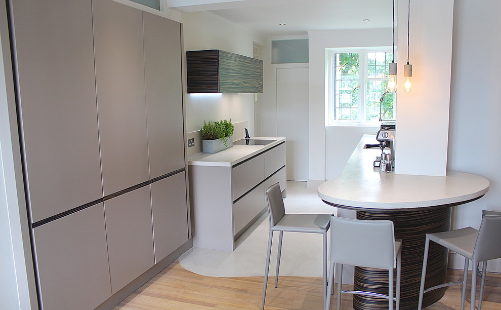 Small contemporary galley open plan kitchen in London with a drop-in sink, flat-panel cabinets, grey cabinets, concrete benchtops, grey splashback, stainless steel appliances, concrete floors and no island.