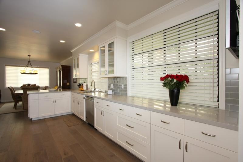 Example of a large transitional l-shaped medium tone wood floor and brown floor eat-in kitchen design in Los Angeles with an undermount sink, shaker cabinets, white cabinets, soapstone countertops, metallic backsplash, subway tile backsplash, stainless steel appliances and a peninsula
