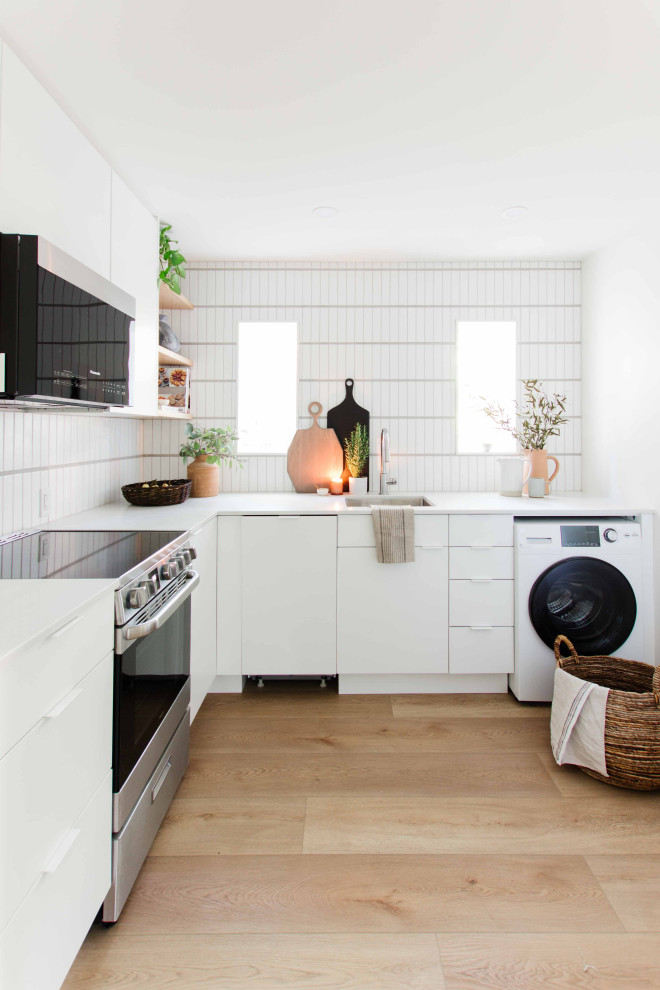 Inspiration for a small contemporary l-shaped separate kitchen in Vancouver with an undermount sink, flat-panel cabinets, white cabinets, quartz benchtops, white splashback, ceramic splashback, stainless steel appliances, vinyl floors, no island, brown floor and grey benchtop.