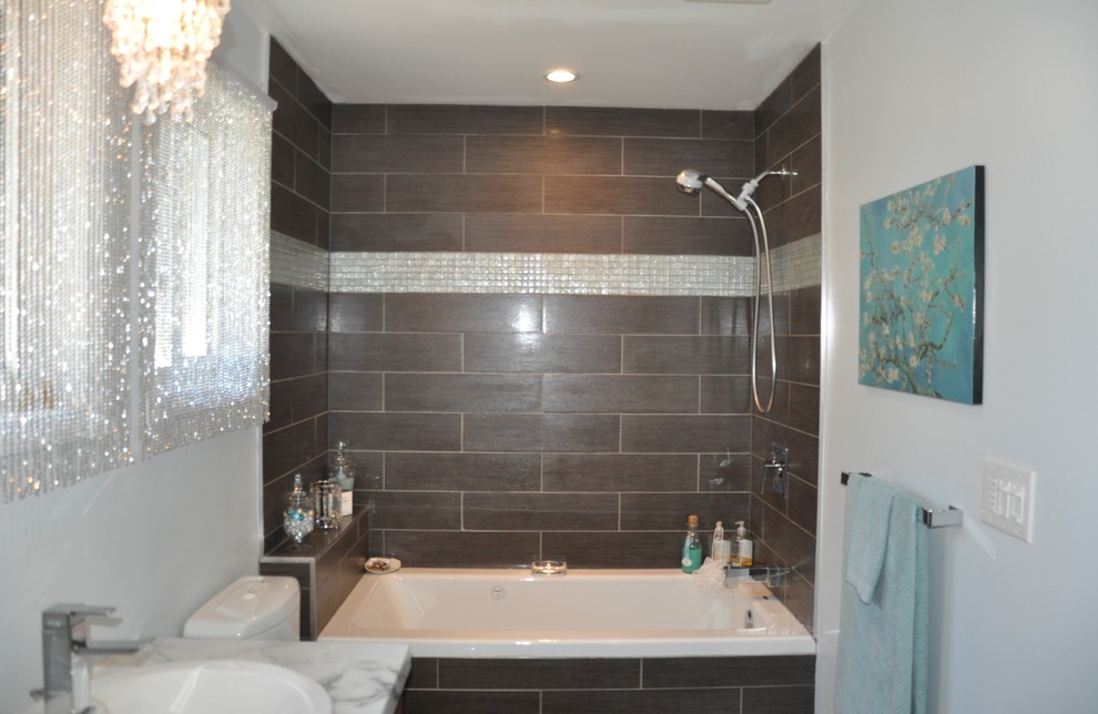 This is an example of a small modern master bathroom in Toronto with flat-panel cabinets, medium wood cabinets, brown tile, a vessel sink, a drop-in tub, a shower/bathtub combo, a one-piece toilet, ceramic tile, grey walls and ceramic floors.