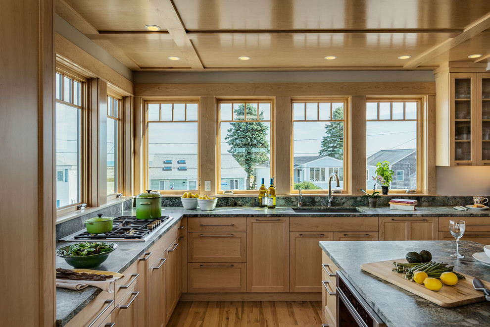 This is an example of a large beach style l-shaped eat-in kitchen in Portland Maine with an undermount sink, recessed-panel cabinets, light wood cabinets, granite benchtops, stone slab splashback, panelled appliances, medium hardwood floors and with island.
