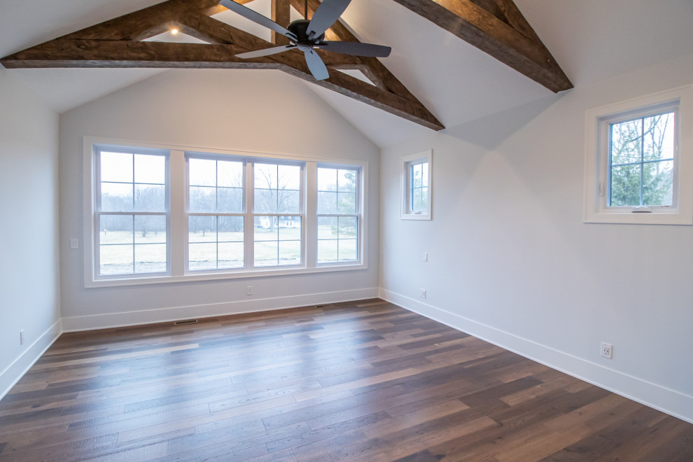 Foto di una grande camera degli ospiti classica con pareti grigie, pavimento in legno massello medio, pavimento marrone e travi a vista