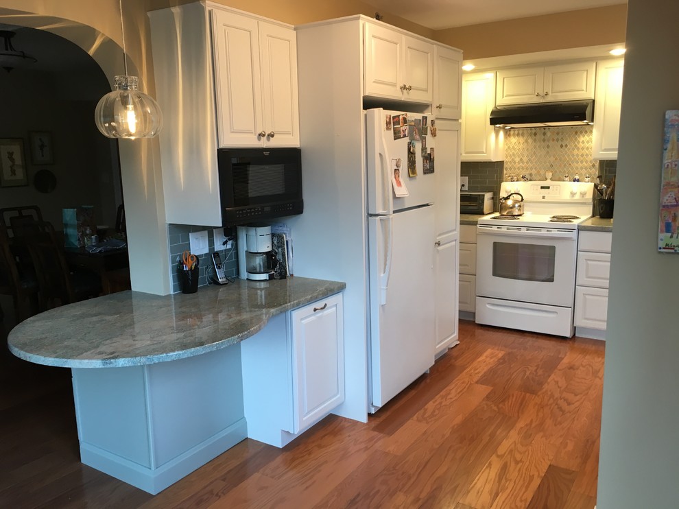 Transitional u-shaped medium tone wood floor kitchen photo in Boston with a drop-in sink, raised-panel cabinets, white cabinets, granite countertops, green backsplash, glass tile backsplash, white appliances, a peninsula and green countertops