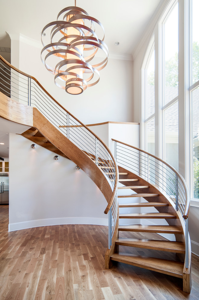 Large contemporary wood curved staircase in Charlotte with open risers.