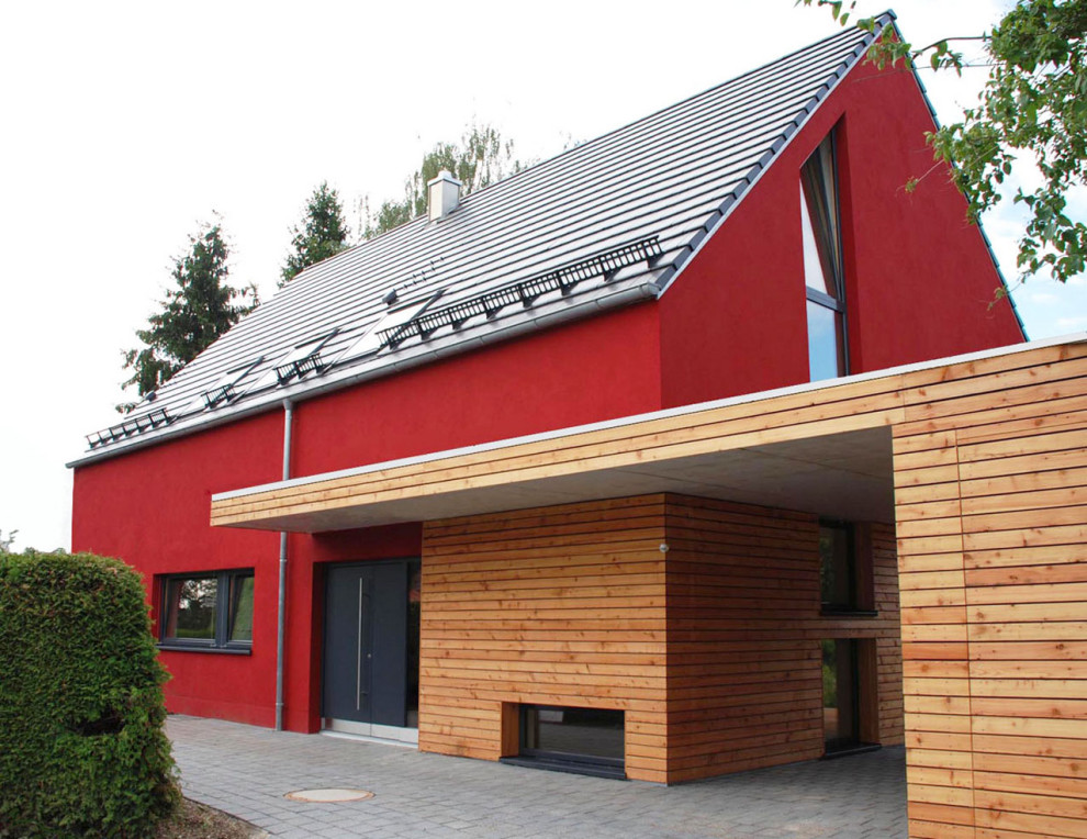 Réalisation d'une façade de maison rouge minimaliste en stuc avec un toit à deux pans, un toit en tuile et un toit gris.