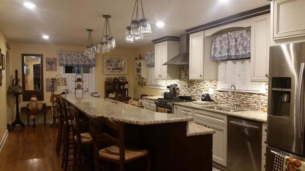 Enclosed kitchen - large transitional single-wall medium tone wood floor and brown floor enclosed kitchen idea in Orange County with an undermount sink, shaker cabinets, white cabinets, granite countertops, gray backsplash, matchstick tile backsplash, stainless steel appliances and an island
