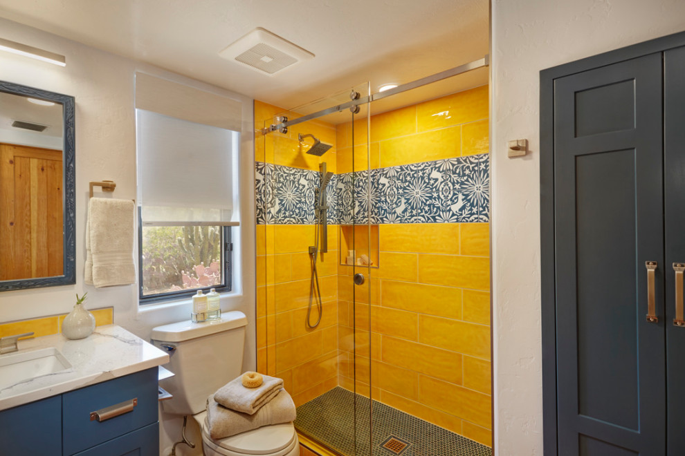 Источник вдохновения для домашнего уюта: маленькая ванная комната в стиле неоклассика (современная классика) с фасадами в стиле шейкер, синими фасадами, открытым душем, раздельным унитазом, желтой плиткой, керамогранитной плиткой, серыми стенами, бетонным полом, душевой кабиной, врезной раковиной, столешницей из кварцита, душем с раздвижными дверями, белой столешницей, тумбой под одну раковину и встроенной тумбой для на участке и в саду