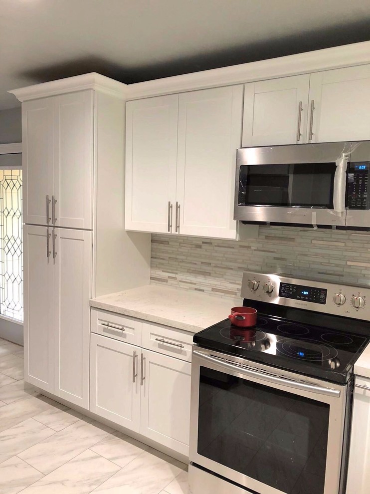 Small transitional u-shaped gray floor enclosed kitchen photo in Houston with an undermount sink, shaker cabinets, white cabinets, quartzite countertops, gray backsplash, stone tile backsplash, stainless steel appliances and no island