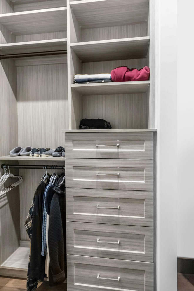 This is an example of a small modern gender-neutral built-in wardrobe in Calgary with shaker cabinets and medium wood cabinets.
