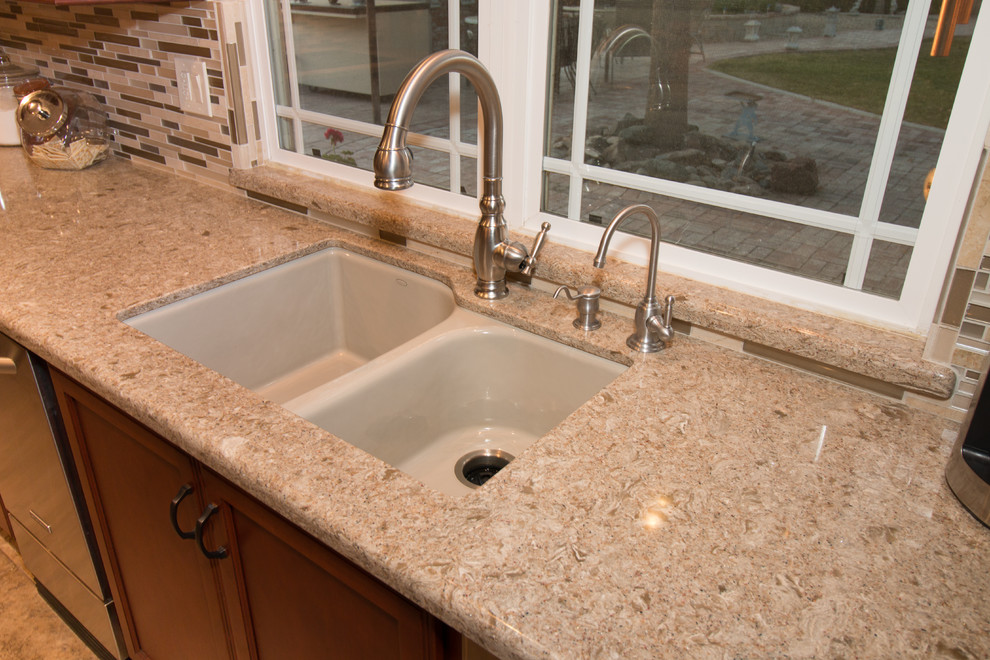 Example of a large transitional u-shaped porcelain tile kitchen design with an undermount sink, flat-panel cabinets, medium tone wood cabinets, quartz countertops, beige backsplash, mosaic tile backsplash, stainless steel appliances and an island