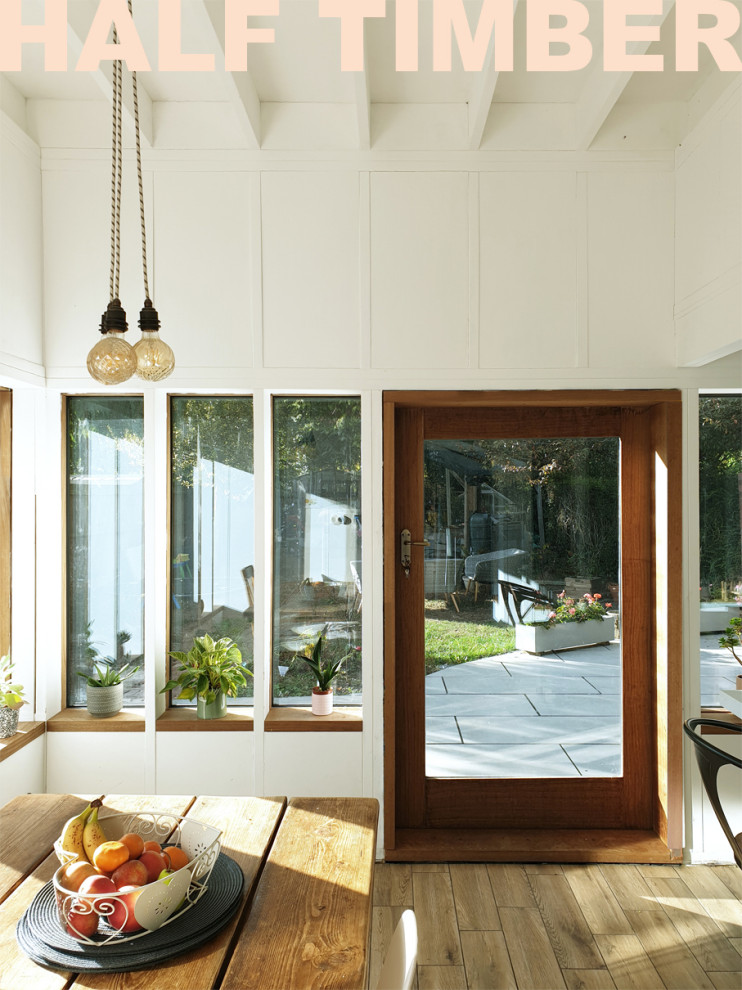 Immagine di una piccola sala da pranzo aperta verso la cucina contemporanea con pareti bianche, pavimento marrone, travi a vista e pannellatura