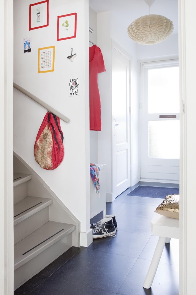 Photo of a contemporary mudroom in Amsterdam with white walls and black floor.