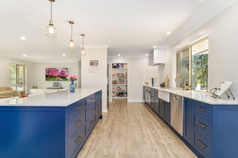 This is an example of a transitional galley eat-in kitchen with a double-bowl sink, blue cabinets, stainless steel appliances and with island.