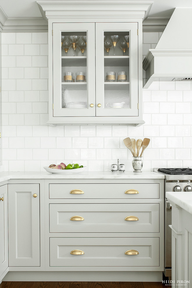 Transitional l-shaped medium tone wood floor eat-in kitchen photo in New York with an undermount sink, gray cabinets, marble countertops, white backsplash, stainless steel appliances and an island