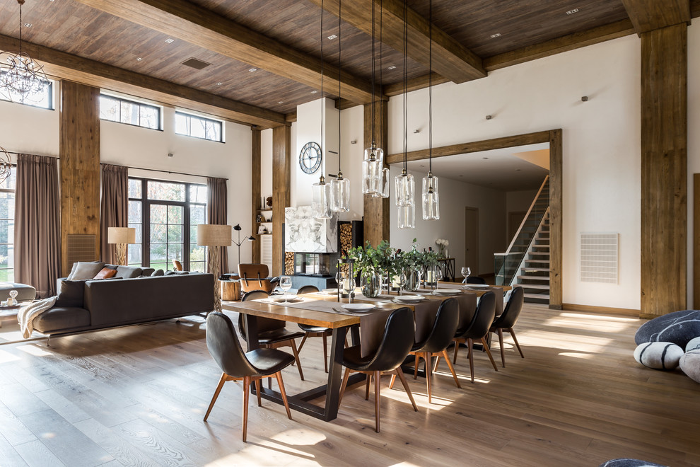 This is an example of an expansive contemporary dining room in Moscow with white walls, medium hardwood floors, a standard fireplace, a stone fireplace surround and brown floor.