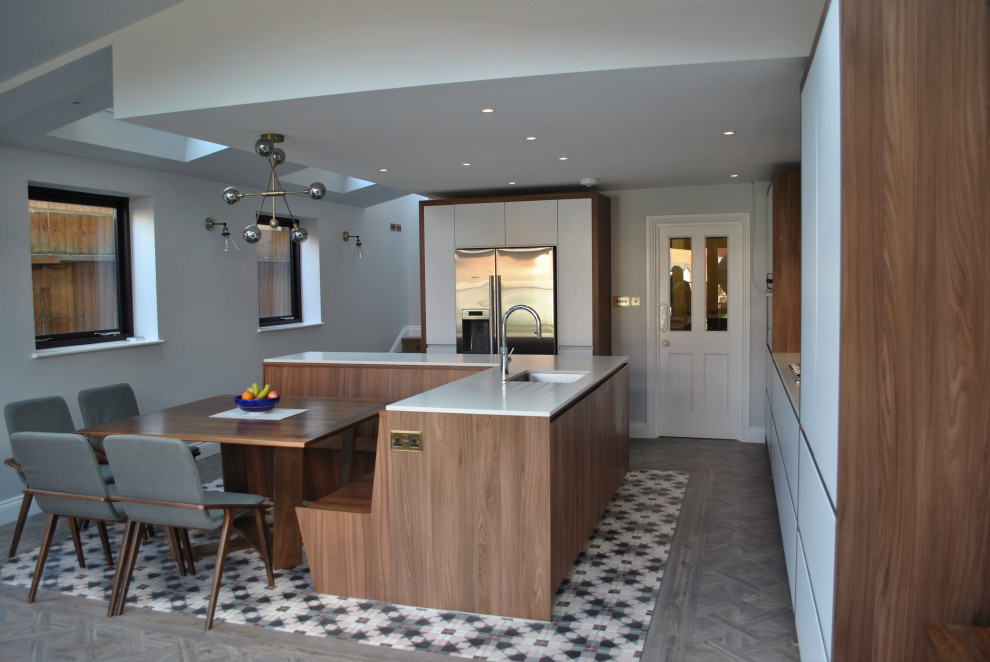 Design ideas for a large modern l-shaped eat-in kitchen in London with an integrated sink, flat-panel cabinets, white cabinets, solid surface benchtops, pink splashback, ceramic splashback, stainless steel appliances, linoleum floors, grey floor and grey benchtop.
