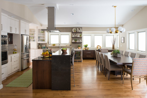Open-concept kitchen and dining space in Mississauga featuring white flat-panel cabinets, stainless steel appliances, a dark wood and black stone island with bar seating, and large windows beside a long dining table.