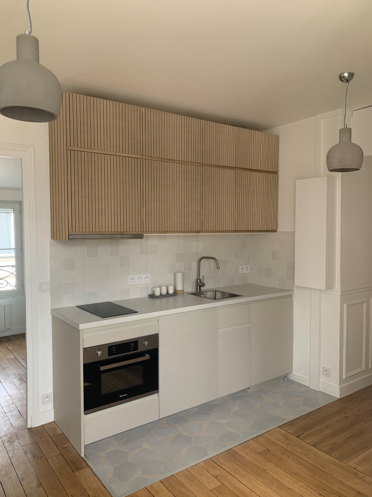Inspiration for a small traditional single-wall open plan kitchen in Paris with an undermount sink, flat-panel cabinets, light wood cabinets, laminate benchtops, white splashback, ceramic splashback, panelled appliances, terra-cotta floors, grey floor and beige benchtop.