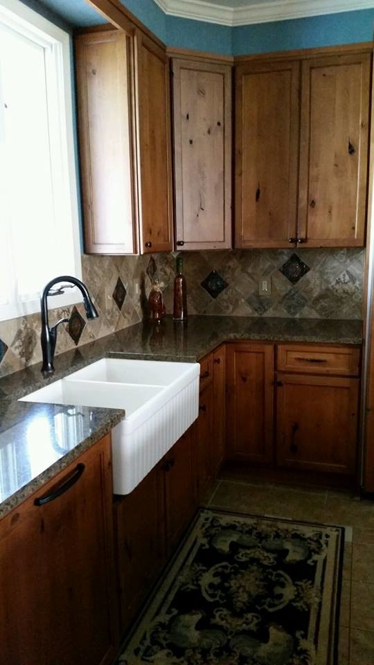 Example of a mid-sized transitional l-shaped ceramic tile and brown floor eat-in kitchen design in Baltimore with a farmhouse sink, flat-panel cabinets, medium tone wood cabinets, granite countertops, gray backsplash, ceramic backsplash, paneled appliances and an island