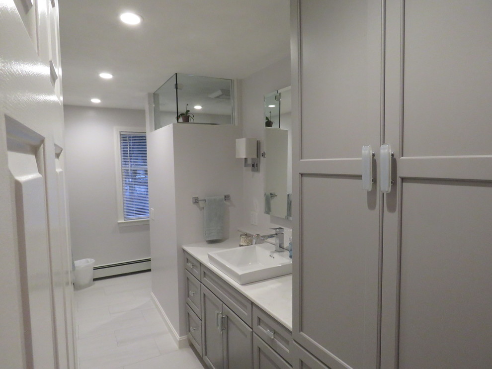 Example of a mid-sized transitional 3/4 porcelain tile alcove shower design in Boston with recessed-panel cabinets, gray cabinets, gray walls, a drop-in sink and marble countertops