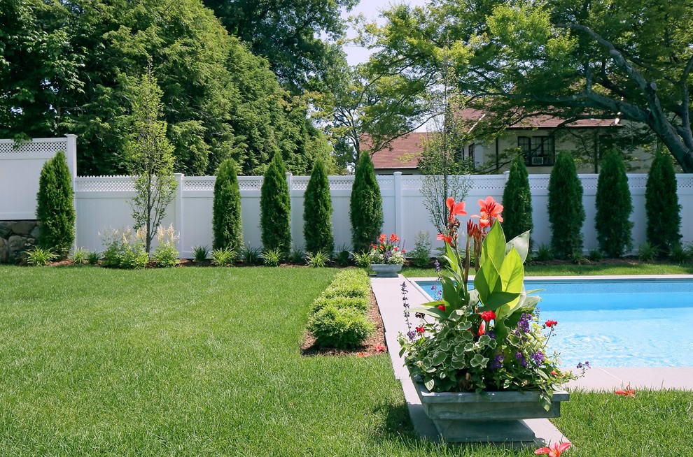 Large modern backyard rectangular pool in New York with natural stone pavers.
