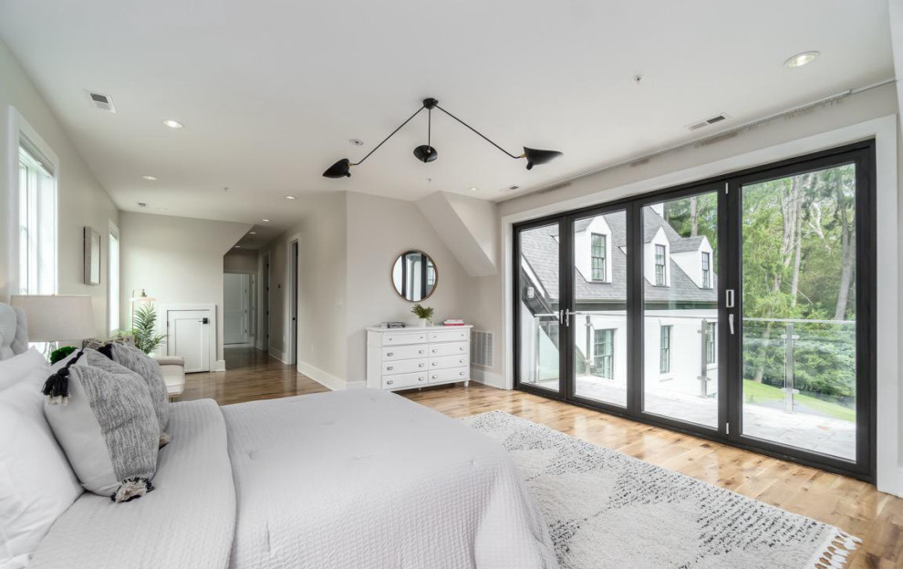 Photo of a contemporary master bedroom in DC Metro with white walls, light hardwood floors and brown floor.