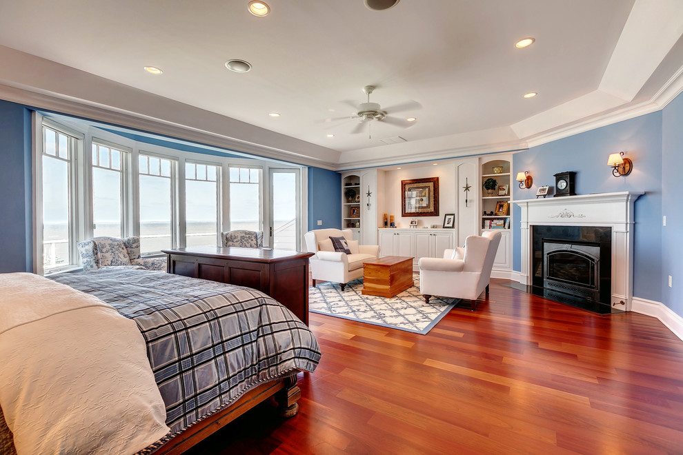 Large traditional master bedroom in Baltimore with blue walls, medium hardwood floors, a corner fireplace and a stone fireplace surround.