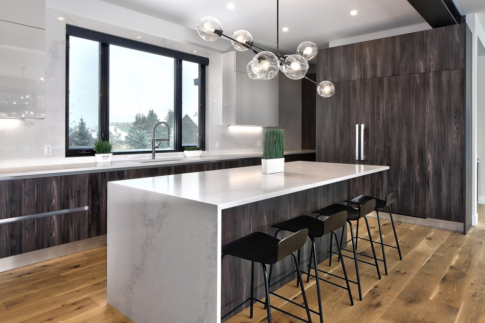 Photo of a contemporary kitchen in Toronto with an undermount sink, flat-panel cabinets, dark wood cabinets, window splashback, panelled appliances, light hardwood floors, with island and white benchtop.