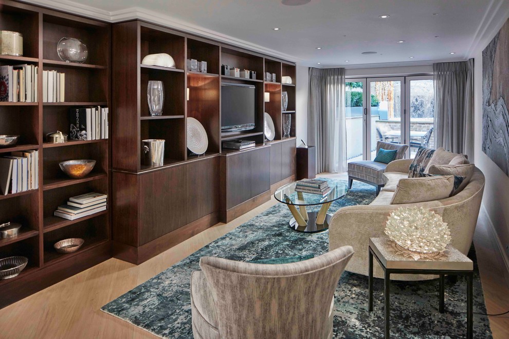 This is an example of a mid-sized contemporary formal open concept living room in London with beige walls, light hardwood floors and a built-in media wall.