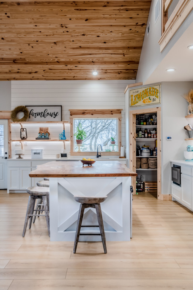 Mid-sized farmhouse l-shaped vinyl floor, beige floor and wood ceiling eat-in kitchen photo in Houston with a farmhouse sink, shaker cabinets, white cabinets, wood countertops, white backsplash, shiplap backsplash, stainless steel appliances, an island and beige countertops