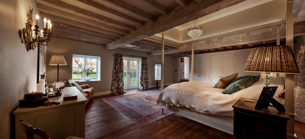Пример оригинального дизайна: большая хозяйская спальня: освещение в стиле кантри с бежевыми стенами, темным паркетным полом, коричневым полом и балками на потолке