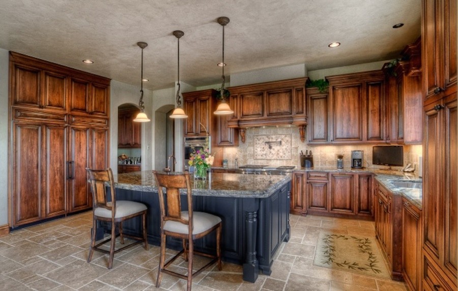 Inspiration for a large traditional u-shaped eat-in kitchen in Denver with a drop-in sink, louvered cabinets, dark wood cabinets, granite benchtops, beige splashback, terra-cotta splashback, stainless steel appliances, terra-cotta floors and with island.