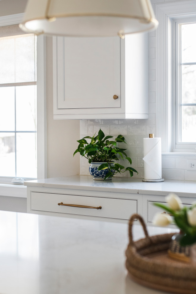 Foto på ett stort vintage vit kök, med en rustik diskho, luckor med profilerade fronter, vita skåp, bänkskiva i kvarts, vitt stänkskydd, stänkskydd i keramik, rostfria vitvaror, klinkergolv i porslin, en köksö och beiget golv