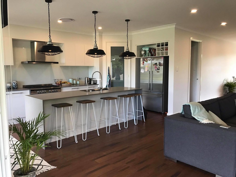 Design ideas for a large contemporary galley open plan kitchen in Sydney with an undermount sink, flat-panel cabinets, white cabinets, concrete benchtops, white splashback, stainless steel appliances, bamboo floors and with island.