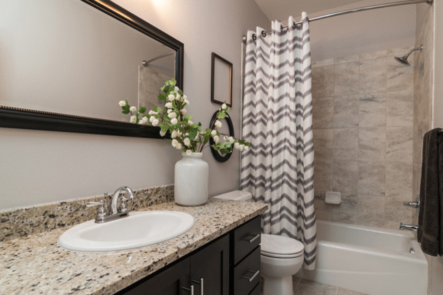 Example of a large transitional kids' beige tile and ceramic tile ceramic tile alcove bathtub design with shaker cabinets, dark wood cabinets, granite countertops, a one-piece toilet, a drop-in sink and gray walls