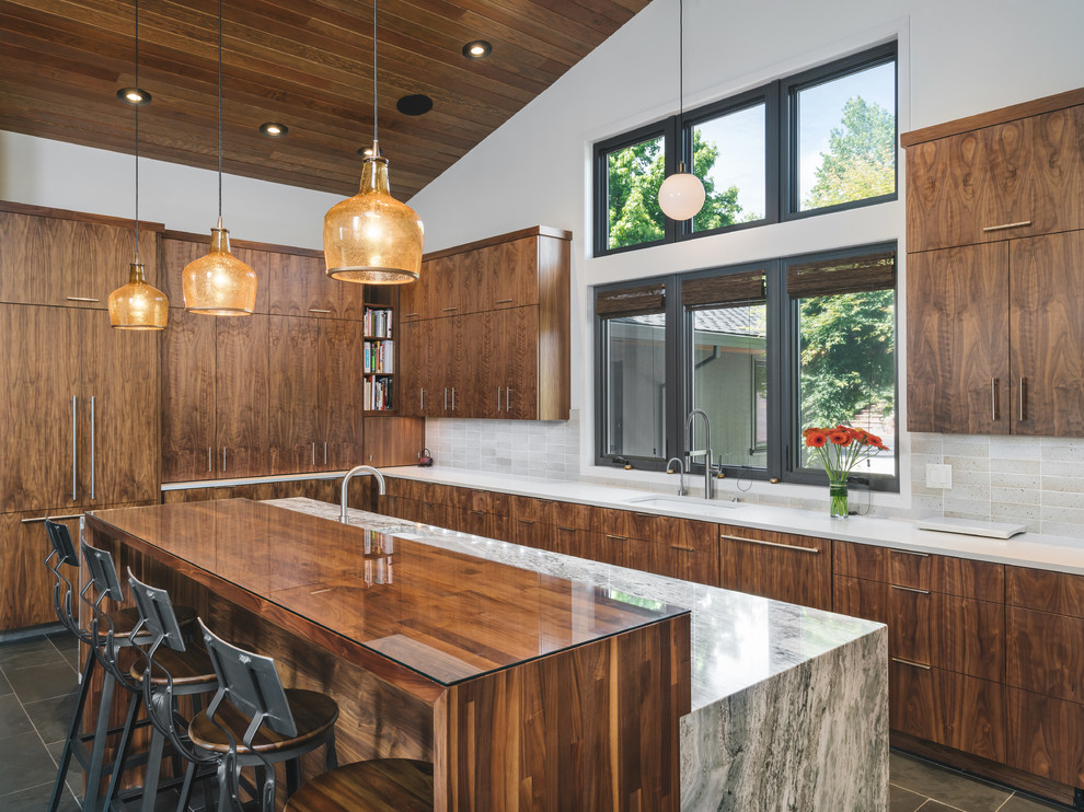 Photo of a midcentury l-shaped kitchen in Portland with an undermount sink, flat-panel cabinets, dark wood cabinets, beige splashback, panelled appliances, with island, grey floor and white benchtop.