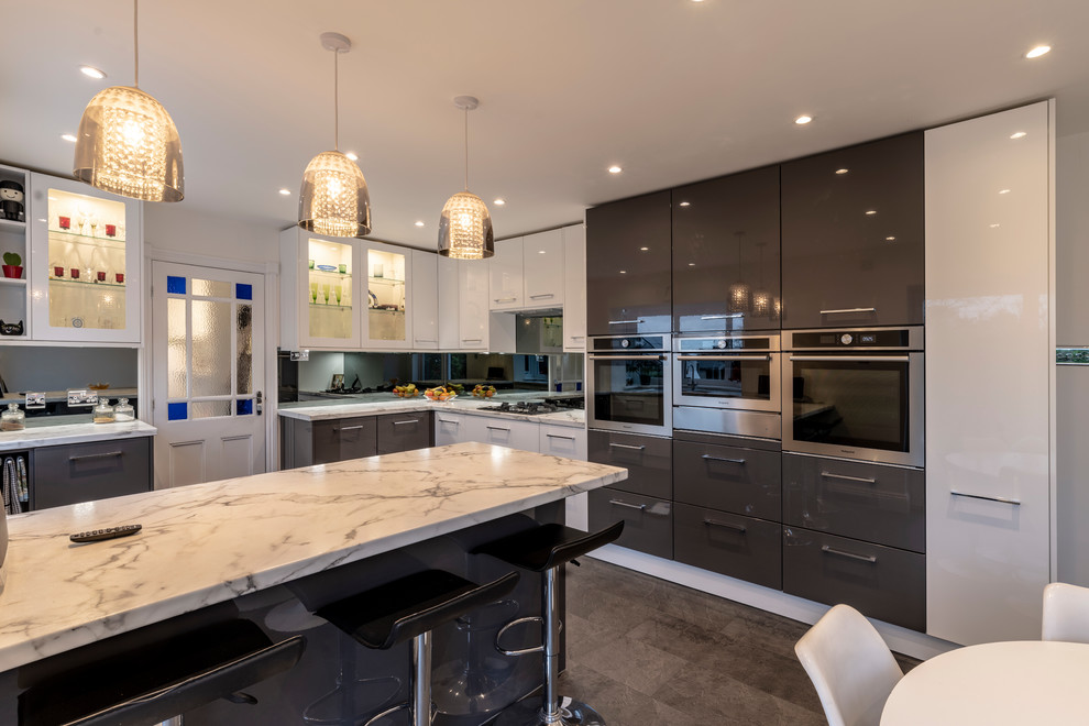 Photo of a mid-sized contemporary eat-in kitchen in Cheshire with flat-panel cabinets, laminate benchtops, grey splashback, glass sheet splashback, black appliances, vinyl floors, grey floor and white benchtop.